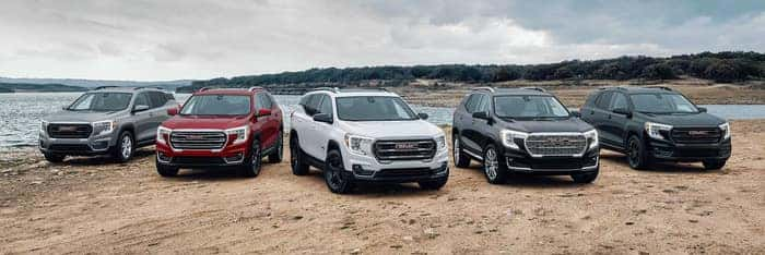 2025 GMC SUV lineup parked off-road showcasing Terrain, Acadia, and More