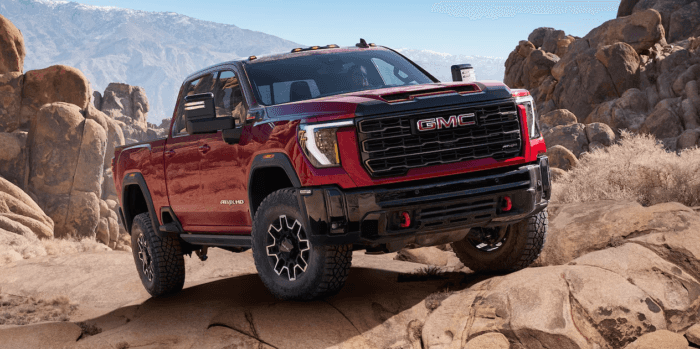 Red 2025 GMC Sierra HD driving on rocks