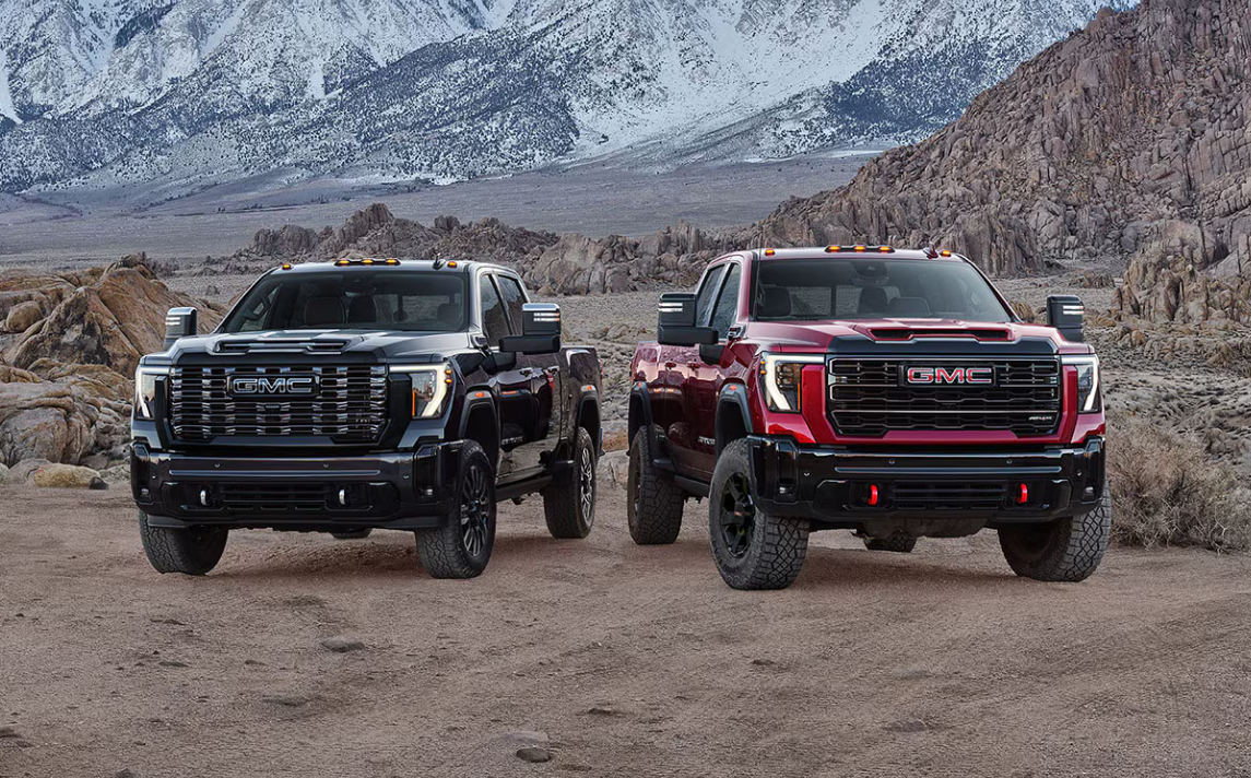 Two GMC trucks parked in dirt