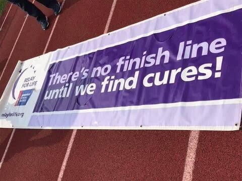 Banner reading “There’s no finish line until we find cures!” on track.