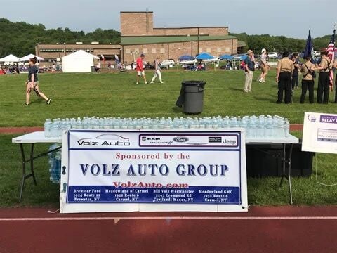 Table with water bottles and a Volz Auto Group sponsor banner.