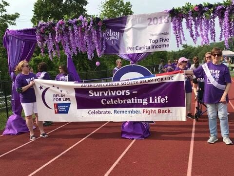 Participants holding a Relay For Life “Survivors – Celebrating Life” banner.