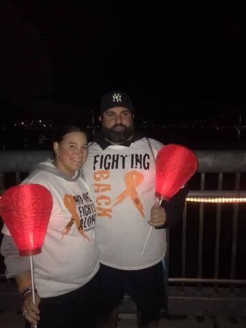 Two people holding red lanterns at a night event.