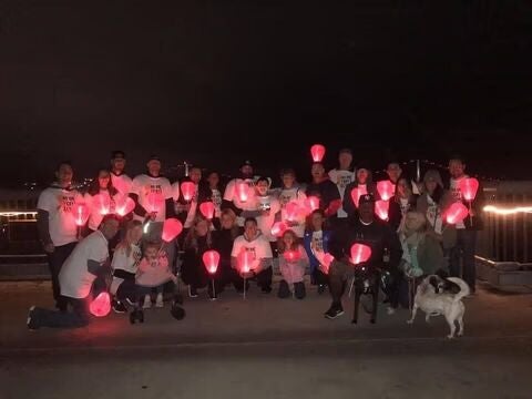 Large group holding glowing red lanterns at night.
