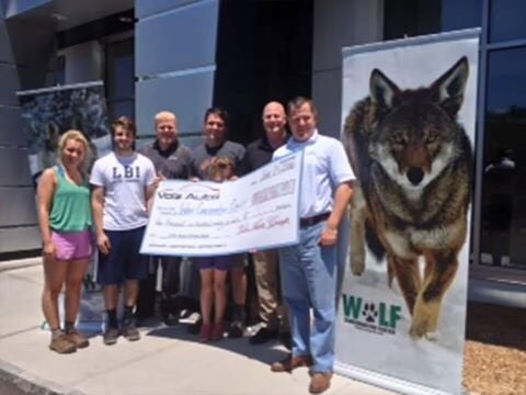 Group holding a donation check with wildlife-themed banners behind them.