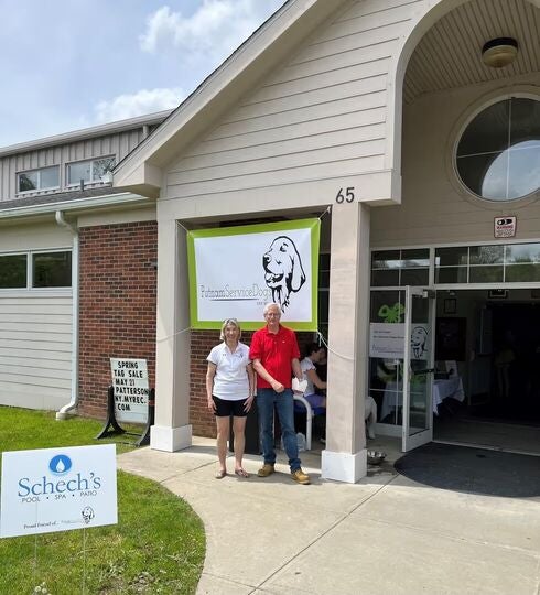 Two people standing outside a building with a Putnam Service Dogs banner.