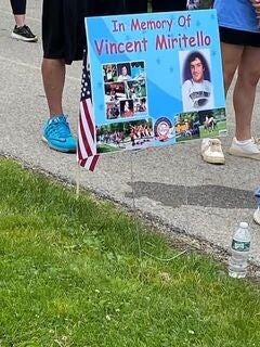 Memorial sign for Vincent Miritello with photos and an American flag.