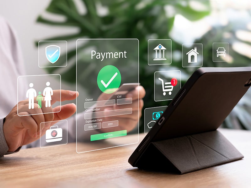 A person uses a smartphone to pay bills online, with a holographic payment form and various app icons.